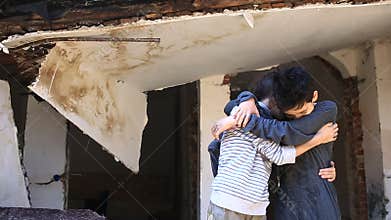 Refugee children are sitting near a ruined house. War, earthquake, fire, bombing