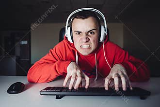Emotional gamer plays the game on the home computer. Angry young man and has his fingers on the keyboard.