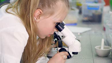 The close-up of the girl looking at the sample in the microscope. 4K.