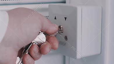 Woman hand put key into white box on wall and pull up guard curtain
