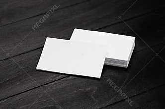 Blank corporate identity business card and stack on black stylish wood background with blur, template.