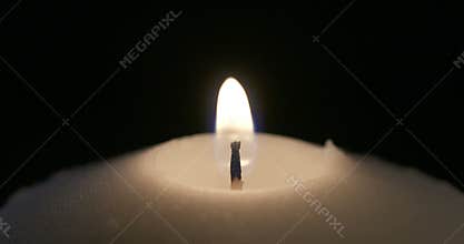 Macro shot of a match lighting a candle on a dark background