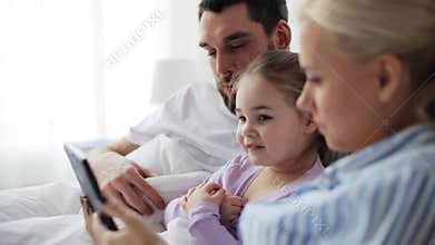 Happy family with tablet pc in bed at home