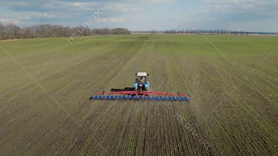 The tractor is working in the field in early spring. Produces harrowing to prevent soil loss of moisture. 4K aerial