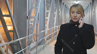 Young woman talking on the phone and walk in the night indoor. Portrait of attractive girl speaking on cellphone. Close