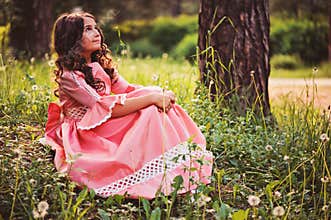 Beautiful child girl dressed as fairytale princess sitting in summer forest