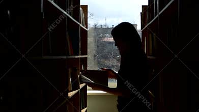 Silhouette of young student reading a book in a