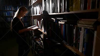 Pretty young college student in a library, chooses