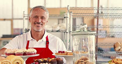Happy server looking at camera with thumbs up behind cakes