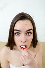 Close up of woman scared funny watching scary movie eating popcorn