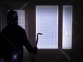 Burglar with crowbar breaking in from back door