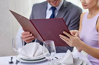 Close up of happy couple with menu at restaurant