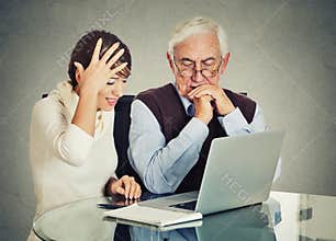 Woman teaching confused elderly man how to use laptop