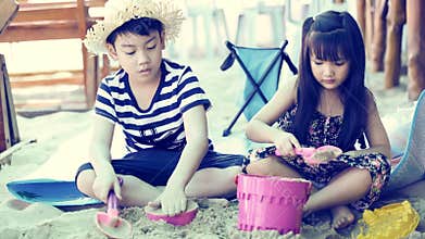 Happy asian kids playing sand on beach