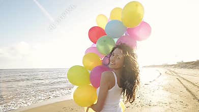 Nice girl playing with balloons on the beach