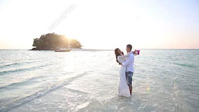bride and groom hug in water at spit against island