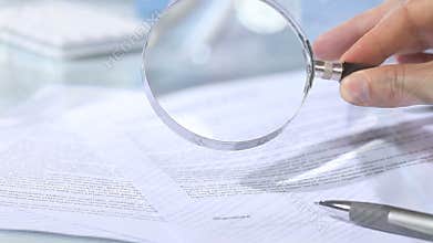 Looking through a magnifying glass to contract and hand signature