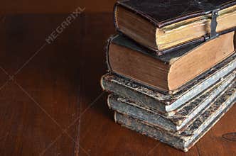 Pile of old books stacked on a wood table