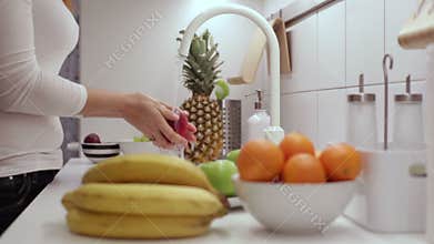 Girl washes a green apple in the kitchen sink