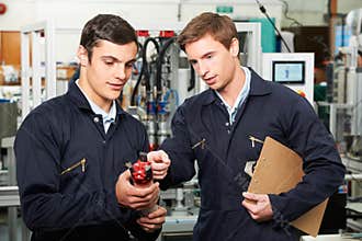 Engineer And Trainee Discussing Component In Factory