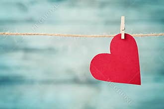 Paper heart hanging on string against turquoise wooden background for Valentines day