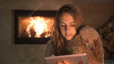 Young woman with her dog sitting on floor and using tablet .