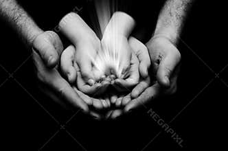 Spark of hope in a child hands wh holding by parents handson dark background. The light of faith