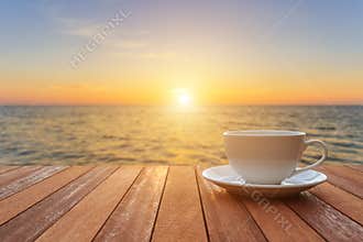 White coffee cup on wood table and view of sunset or sunrise background