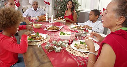 Camera tracks around table as extended family group enjoy Christmas meal together