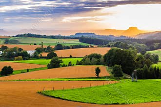 Beautiful sunset over countryside landscape of rolling hills with sun beams piercing sky and lighting hillside