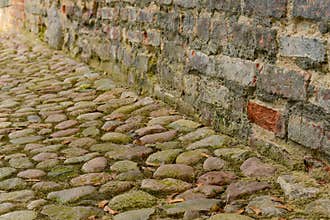 Cobble stone path along grunge brick wall