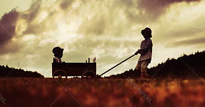Two little brothers playing with the wooden carriage