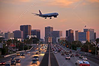 Jet aircraft on landing approach flying low over city freeway