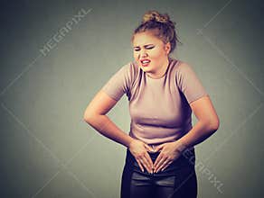 Young woman hands on stomach having bad aches pain. Food poisoning, influenza, cramps.