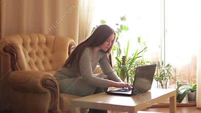 Beautiful young woman using a laptop for social networking in room.