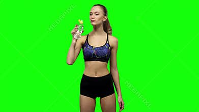 Woman in sportswear drinking water from bottle. Green screen