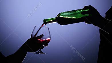 Sommelier pouring red wine inti glass. Back light