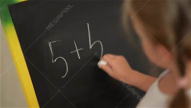 Schoolchild Practicing simple math on chalk board
