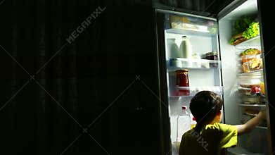 Child eating in front of the refrigerator in the middle of the night.