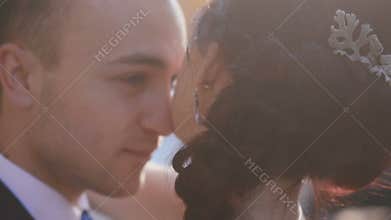 Lovely groom gently holding and kissing his new wife after ceremony. Camera is slowly lifting from waistline to faces
