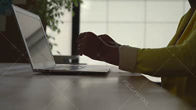 Unrecognisable woman typing on the computer in the modern office with big windows .