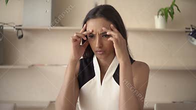 Portrait young indian woman suffer from migraine headache in the office.