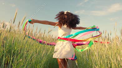 Young girl running with colored ribbons in her hands through the wheat field