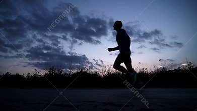 Silhouette of a man running on the road at sunset