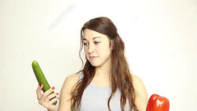 Beautiful young woman eating an vegetables. holding cucumber and red pepper. healthy food - healthy body concept