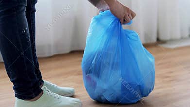 Woman tying bag with garbage at home