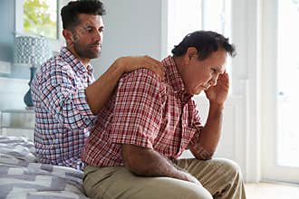 Adult Son Comforting Father Suffering With Dementia