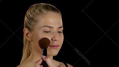 Application of powder on the face. Makeup. Black. Closeup