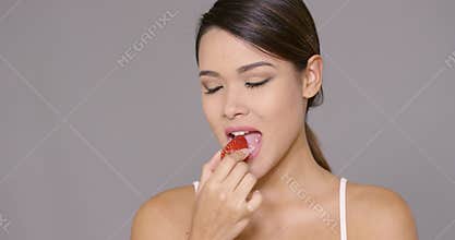 Sensual young woman biting into a strawberry