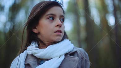 Charming little girl with a brown scared eyes and long brunette hair. A frightened child is standing in the middle of